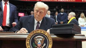 Donald Trump sings the first executive order during the inaugural parade inside Capital One Arena on the inauguration day of his second presidential term, in Washington, U.S. January 20, 2025. REUTERS/Carlos Barria