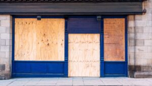 A traditional British shopfront, closed and boarded up with wooden boards